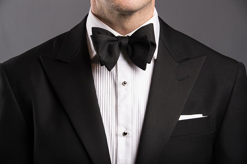 Man wearing a black bow tie with a tuxedo at a formal event