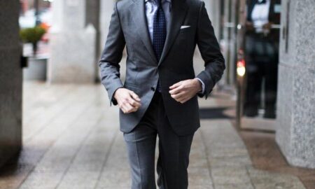 Man in a charcoal grey suit walking on the street