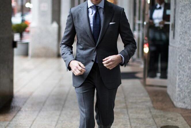 Man in a charcoal grey suit walking on the street