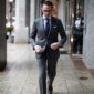 Man in a charcoal grey suit walking on the street