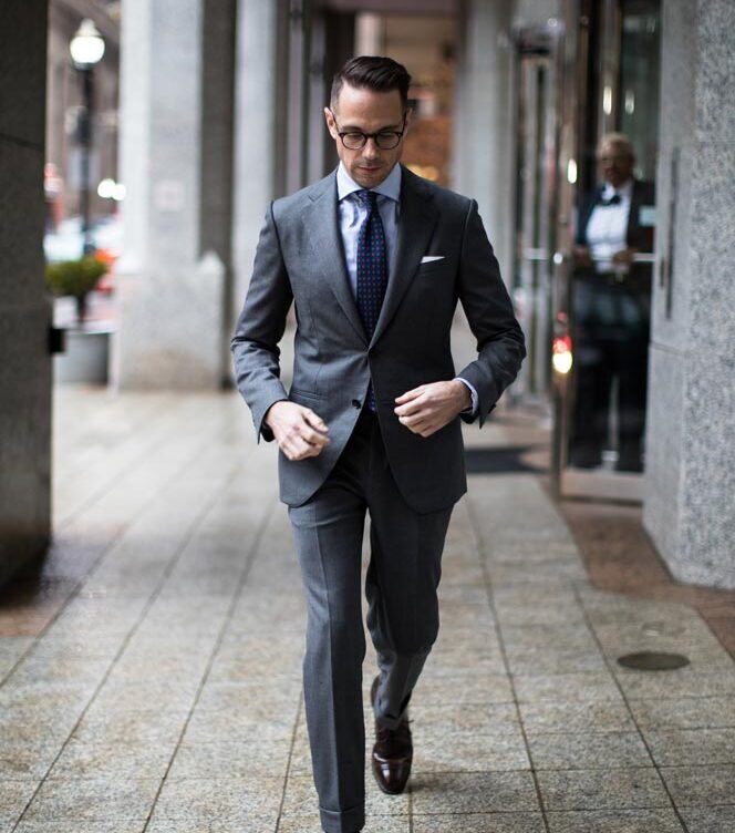 Man in a charcoal grey suit walking on the street